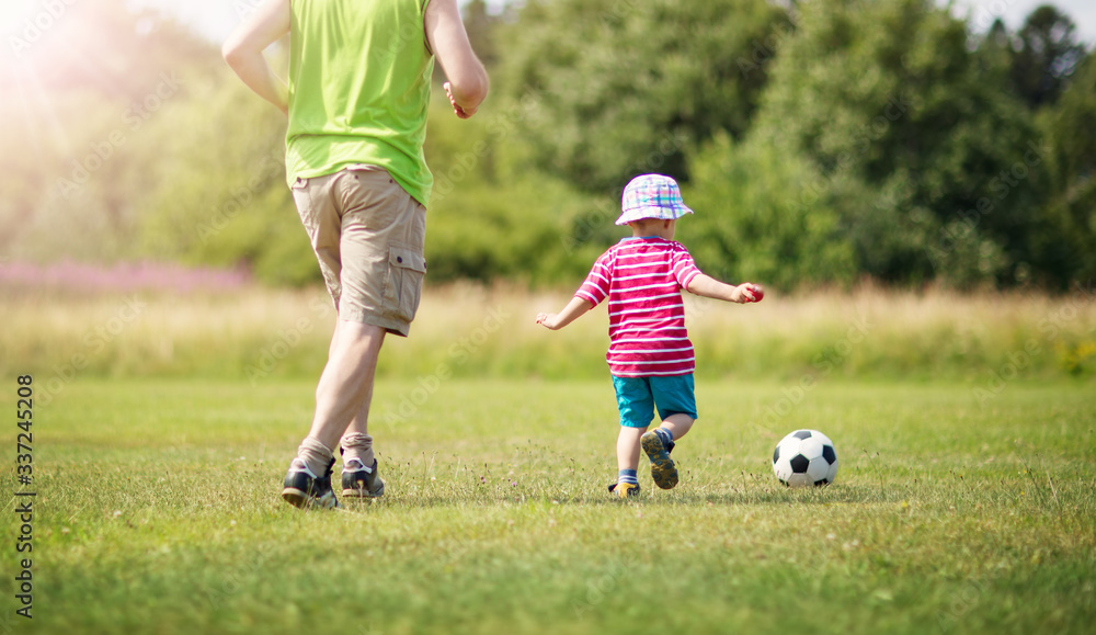 Little boy playting football on the field with gates