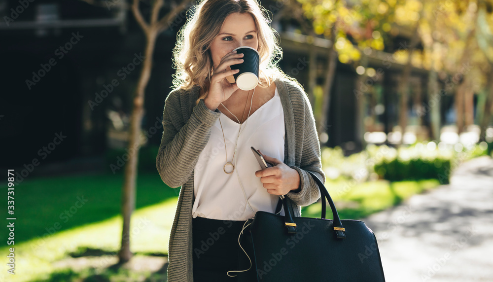 Businesswoman having coffee while commuting in the city