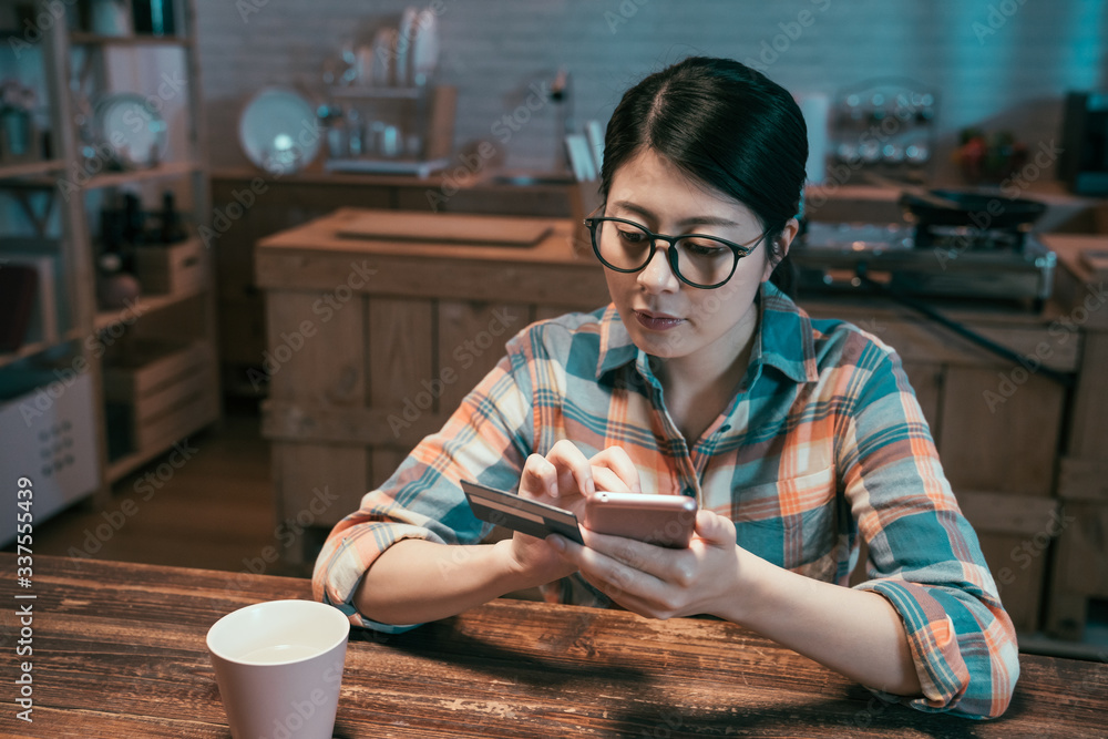 戴眼镜的亚裔日本年轻女子在家用智能手机用信用卡在线购物。el