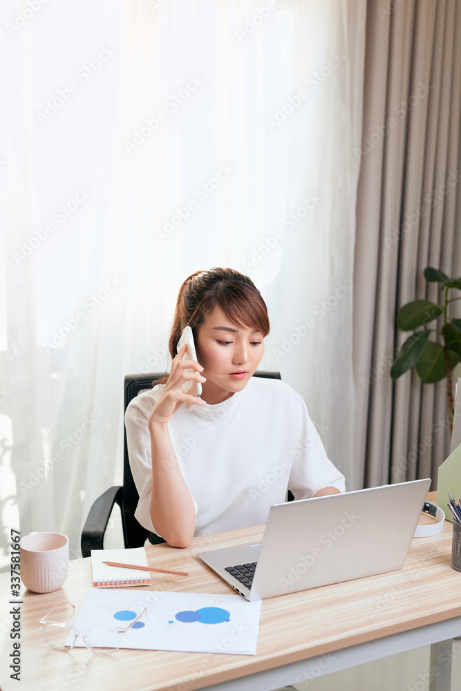 亚洲女性在办公室用笔记本电脑打电话