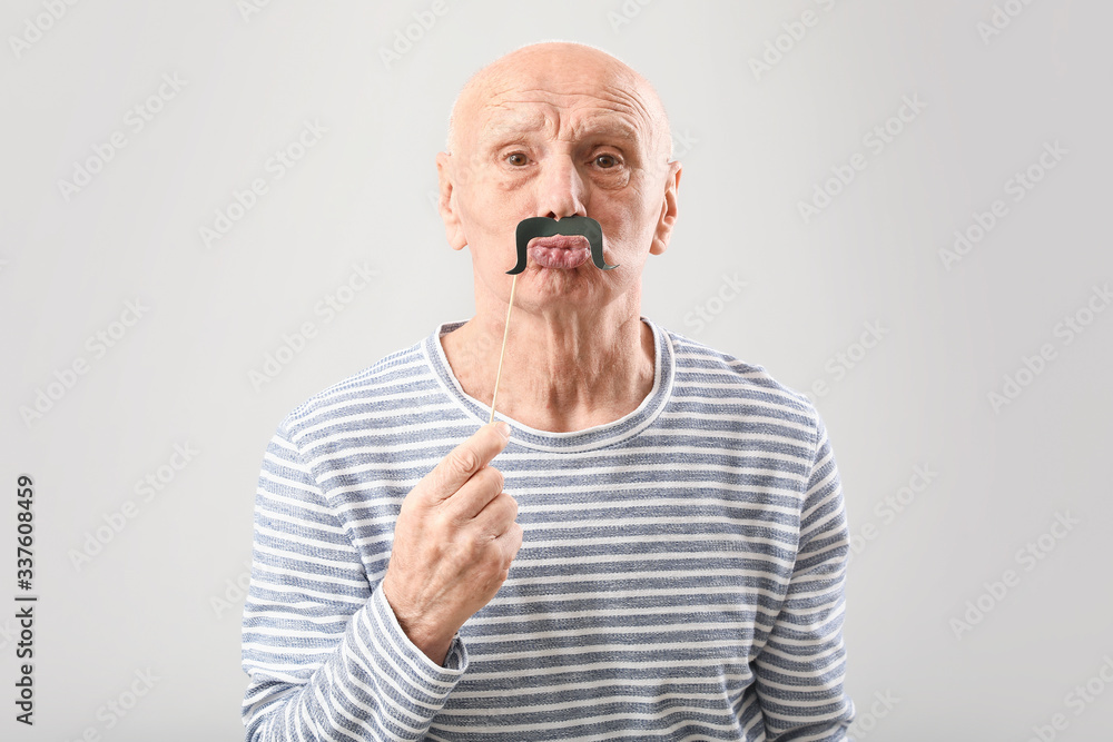 Portrait of elderly man with party decor on grey background