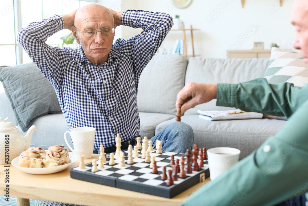 Elderly men playing chess at home