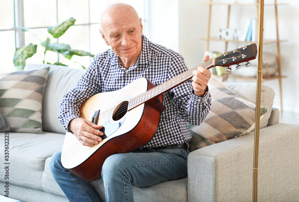 Elderly man playing guitar at home