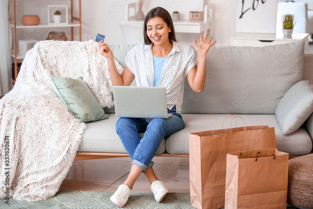 Young woman with laptop and credit card at home. Online shopping concept