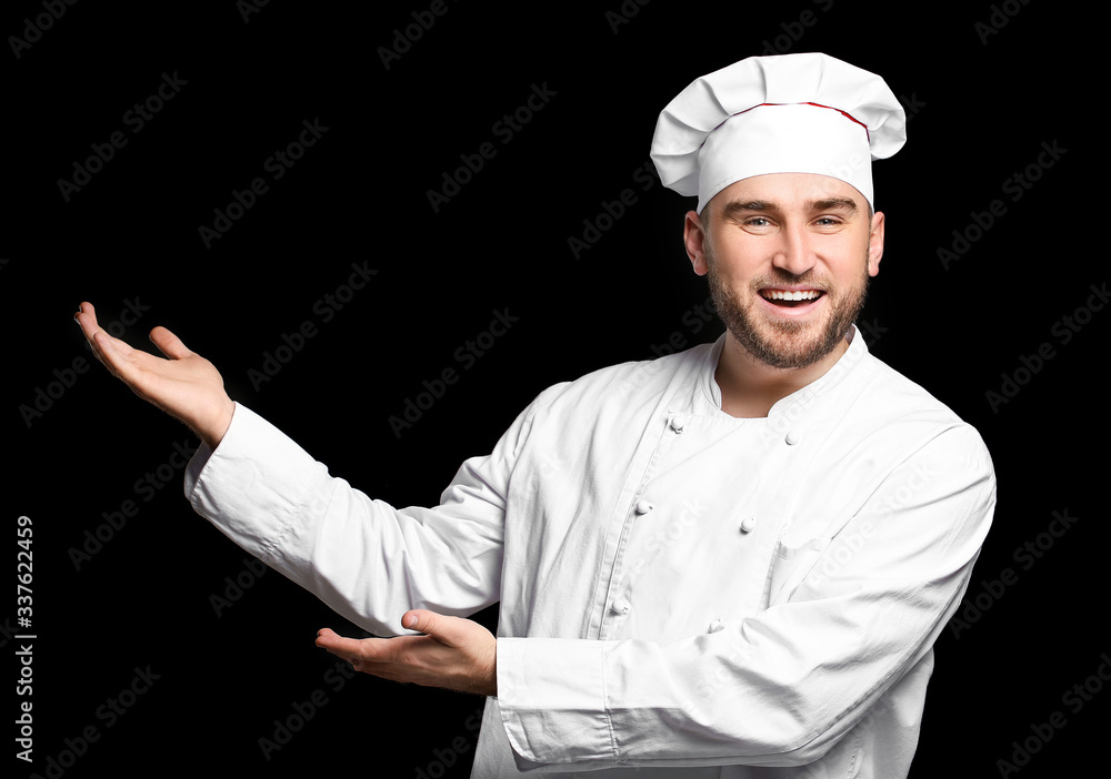 Handsome male chef showing something on dark background