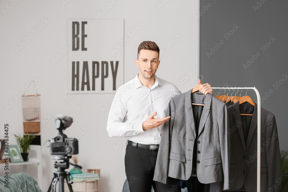 Young male stylist near rack with clothes in studio