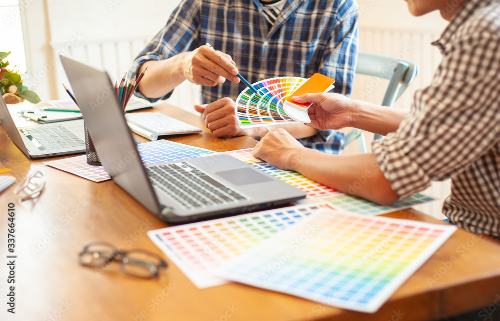 Graphic designers discuss and select color samples for design work.