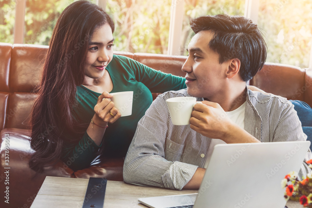 Happy Asian couple drink coffee at home. Love relationship and lifestyle concept.