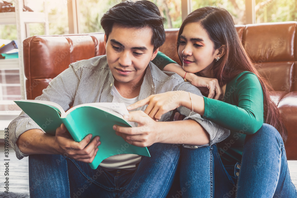 Young Asian couple reading book in living room. Love relationship and lifestyle concept.