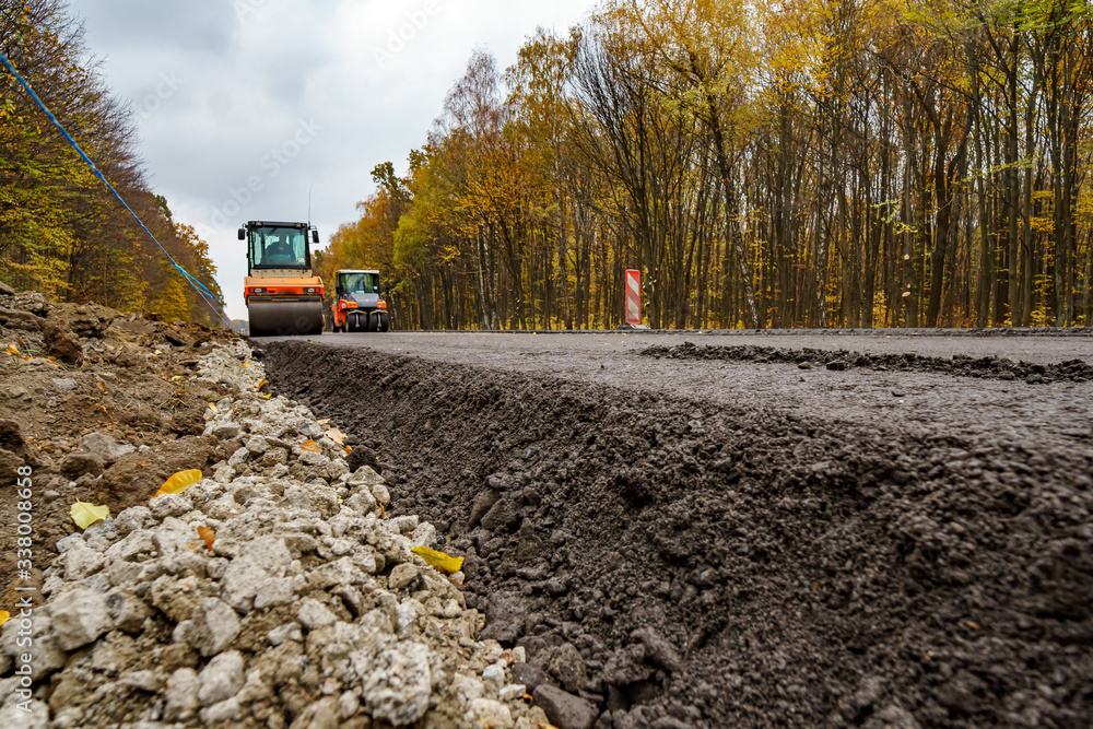 重型机械在蓝天下进行道路重建。从下面看。新鲜的沥青，新的道路。