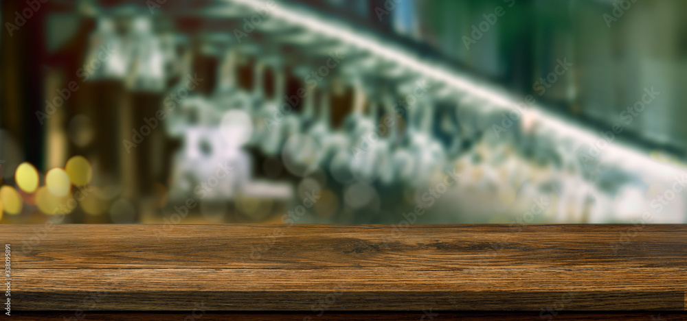 Empty wooden table in front of blurred bar background with light and bokeh for product montage displ