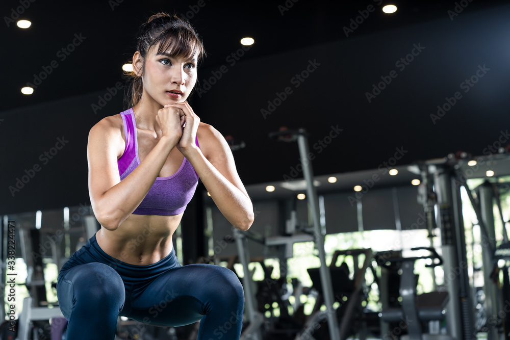 Young pretty Asian girl are working out in Gym showing six packs good body abs. Woman doing a squat 