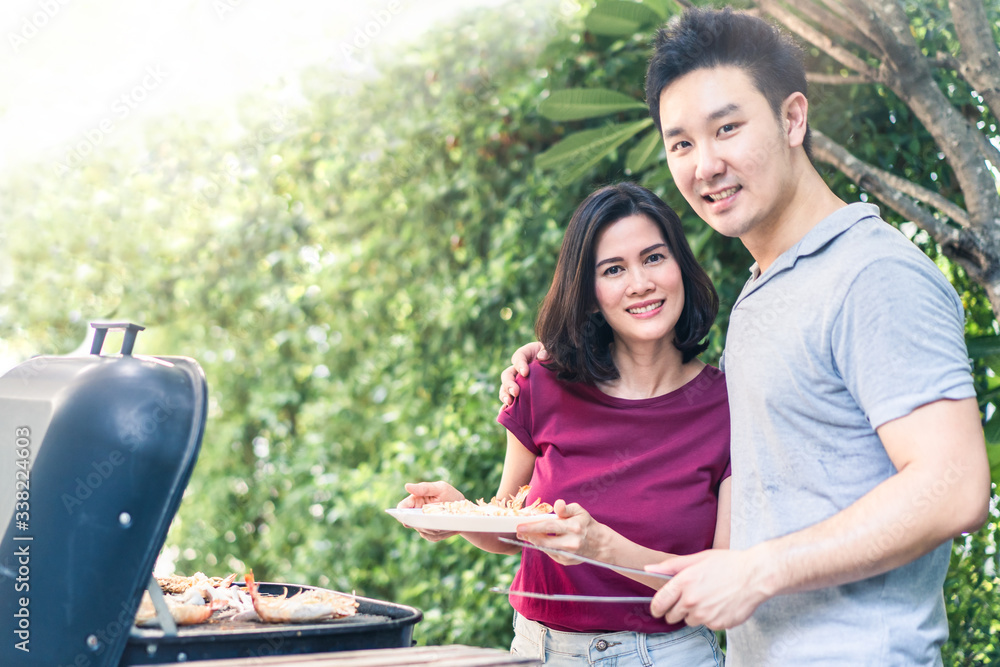 Asian young couple man and woman having small party grill lobster, big prawn seafood barbecue dinner