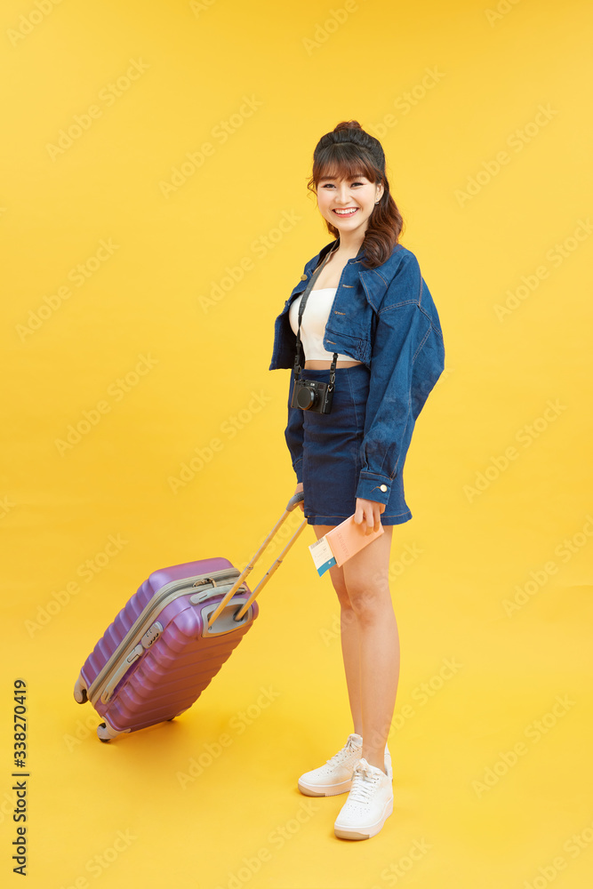 travel, tourism and people concept - smiling young woman with airplane ticket and bag