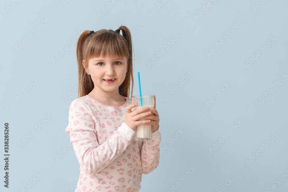 Little girl with glass of milk on grey background