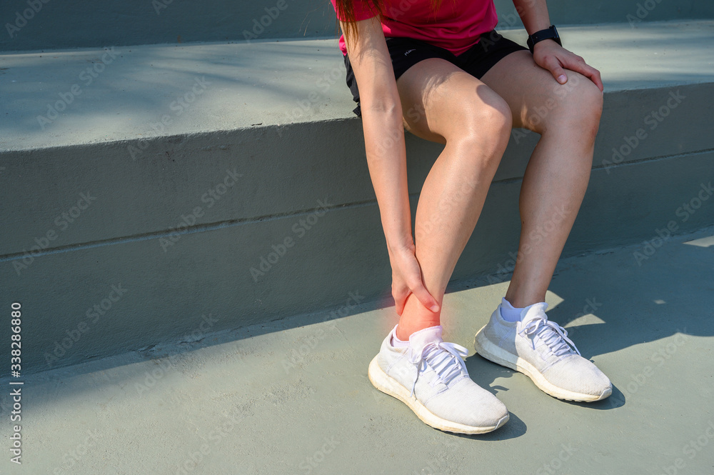 Cropped shot of woman runner suffering from ankle pain. Ankle pain may be caused by an injury, like 