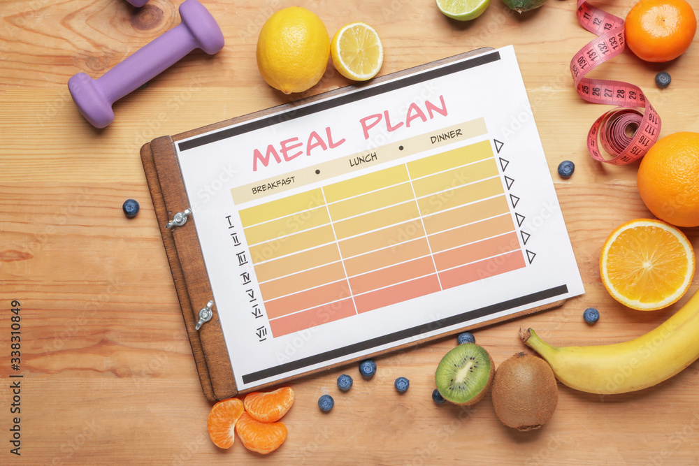 Healthy products, meal plan, measuring tape and dumbbell on wooden background