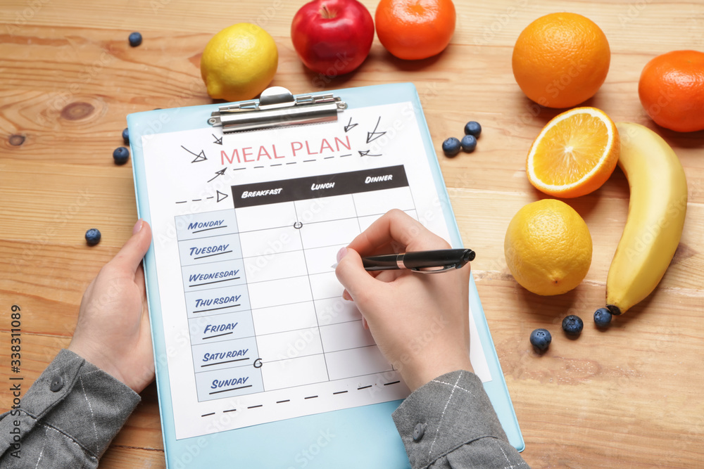 Woman making meal plan on wooden background