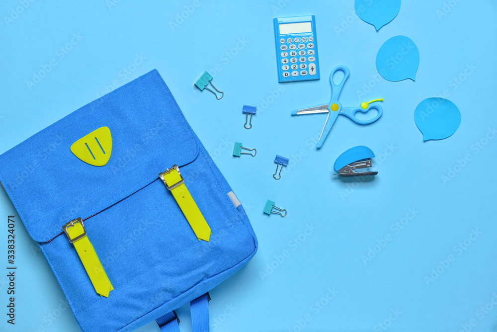 School backpack and stationery on color background