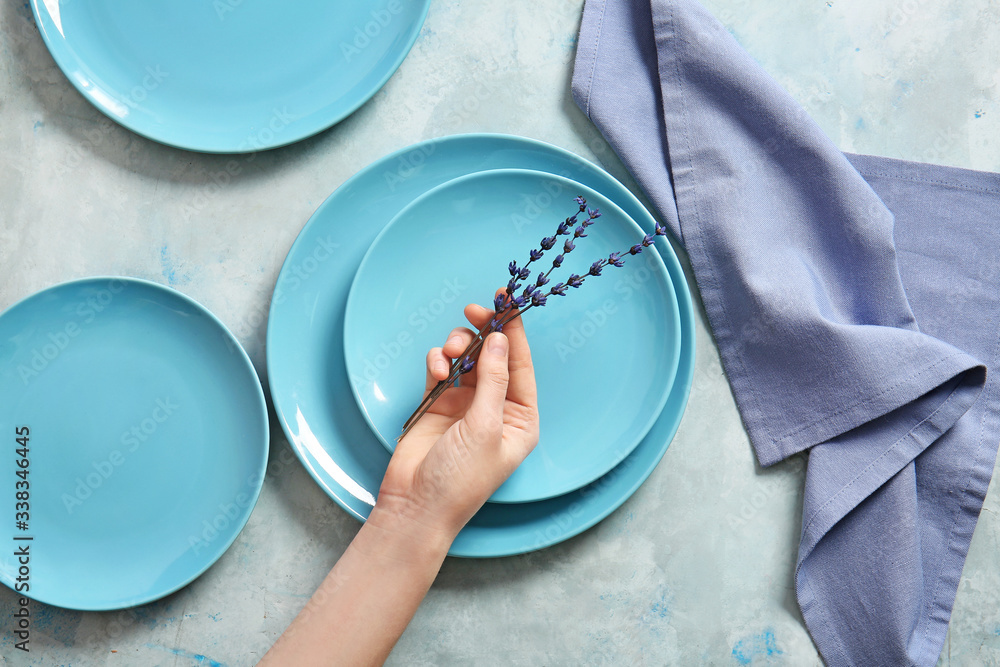 Woman at table with clean plates and flowers, top view