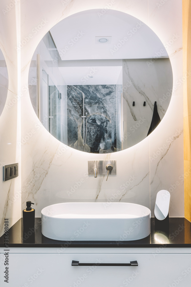 Modern sink and round mirror with led light in a luxury bathroom