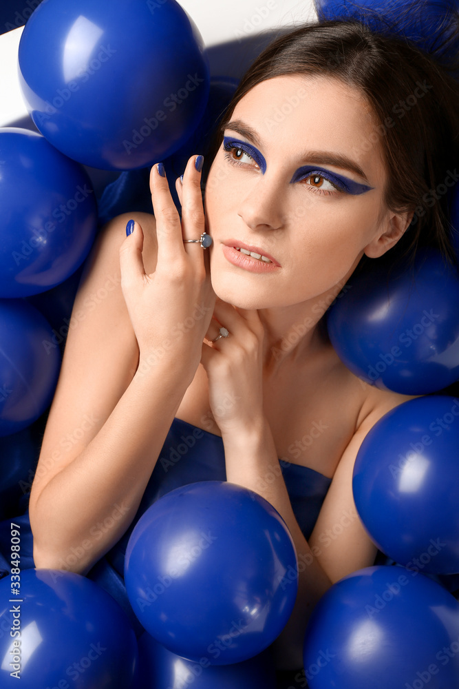 Portrait of fashionable young woman with air balloons lying in bathtub