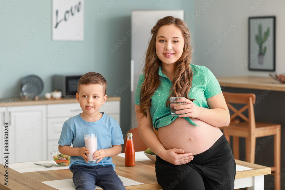 Beautiful pregnant woman and her little son in kitchen