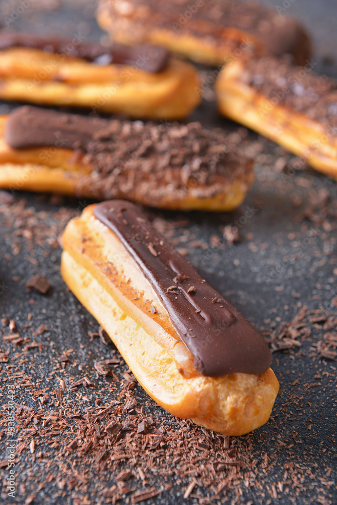 Tasty chocolate eclair on dark background