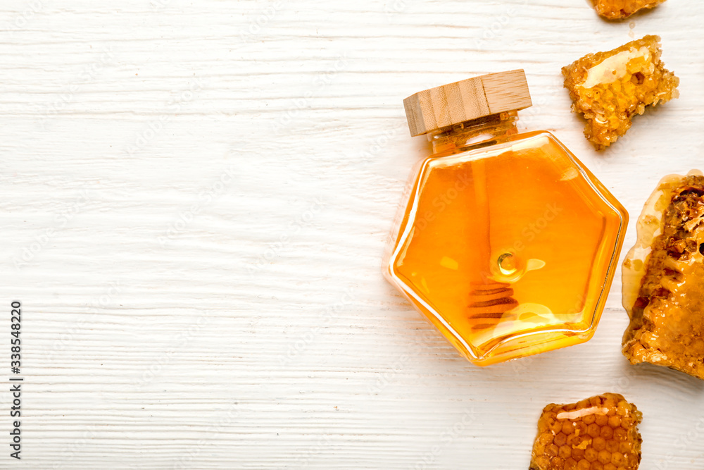 Jar of sweet honey on white wooden background