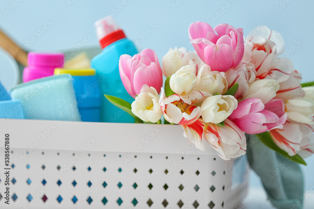 Set of cleaning supplies and spring flowers on color background, closeup