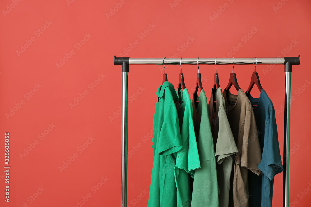 Rack with modern clothes on color background