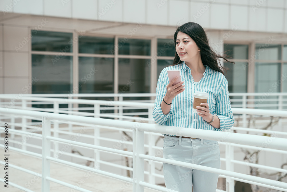 young smiling asian chinese businesswoman walking on bridge outdoor in office work center using smar