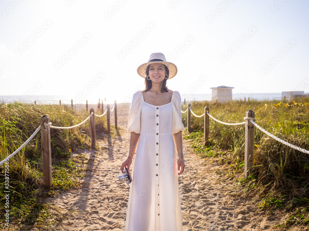 Attractive girl in a white dress with a retro camera