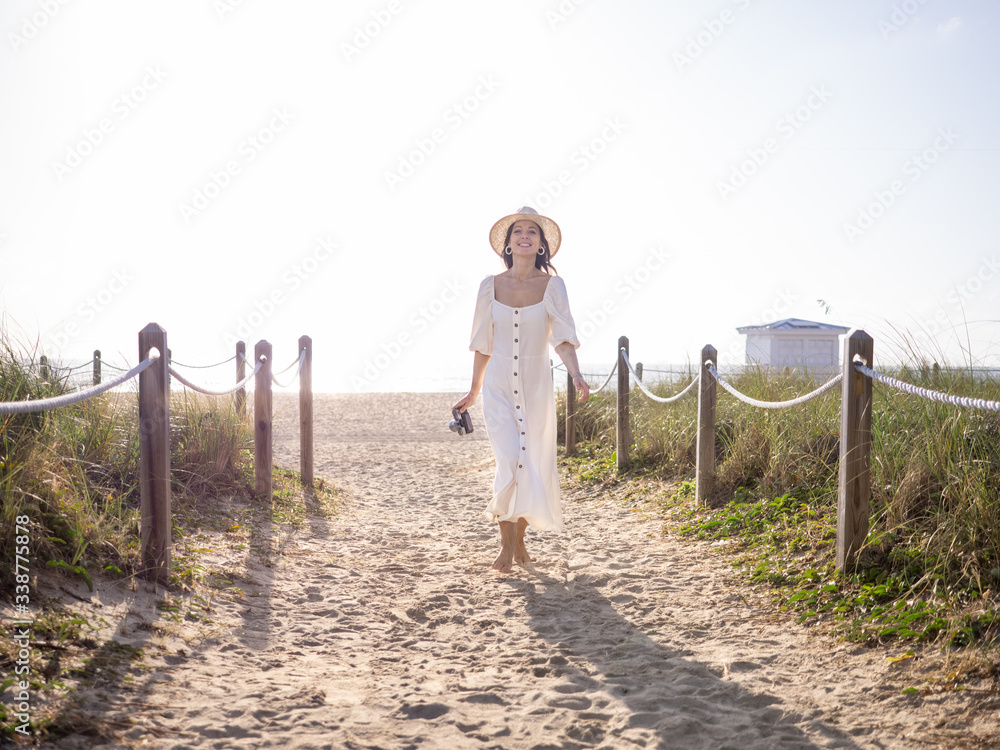 迈阿密海滩上带着复古相机微笑的女人