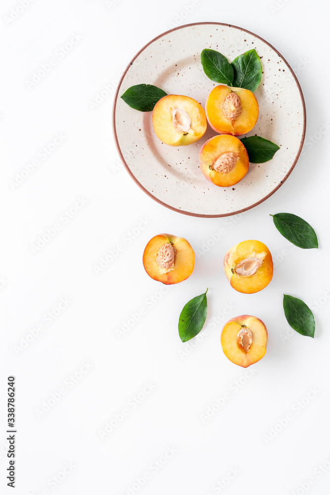 Healthy food. Ripe sliced peaches on plate on white table top-down copy space