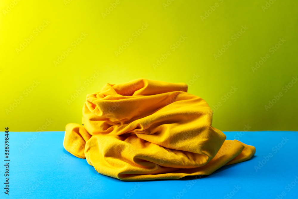 Pile of dirty laundry clothes on blue table Yellow light background.