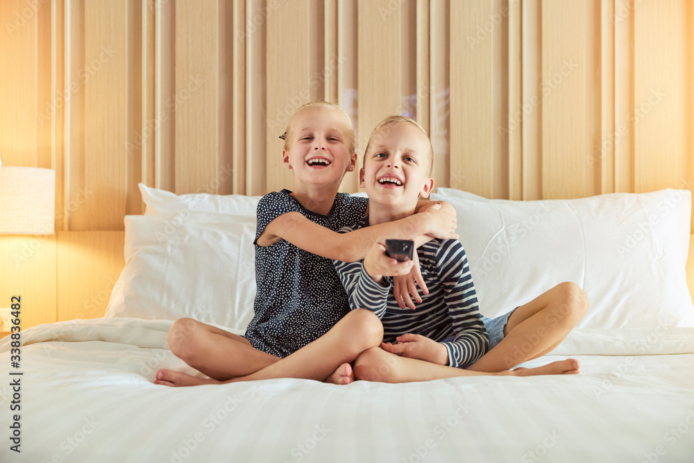 Cute little girl hugging her brother while watching television t