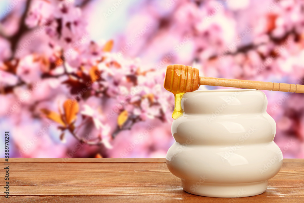 Jar with sweet honey on wooden table outdoors