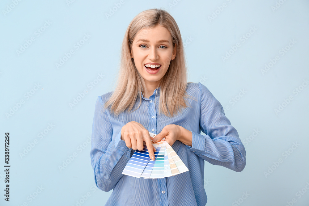 Young woman with paint palette on color background