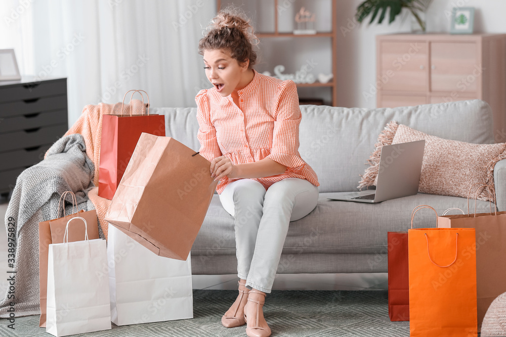 Beautiful young woman with shopping bags at home