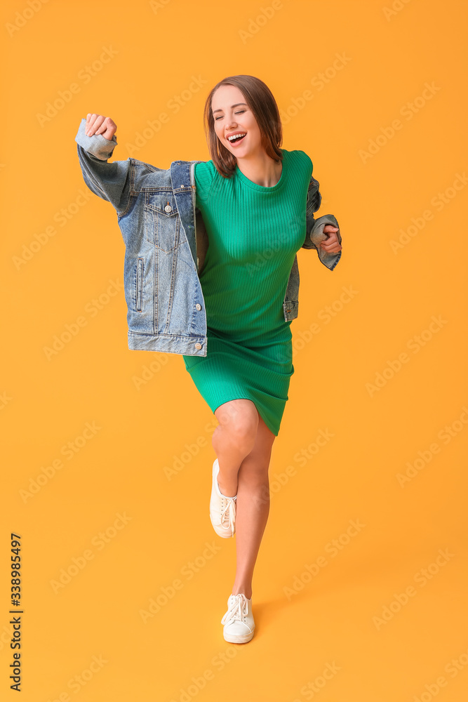 Beautiful young woman dancing against color background