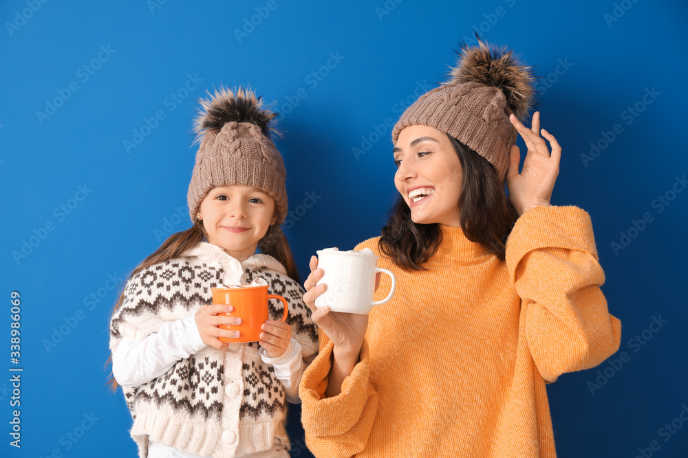 女人和她的小女儿在彩色背景上喝着美味的可可饮料