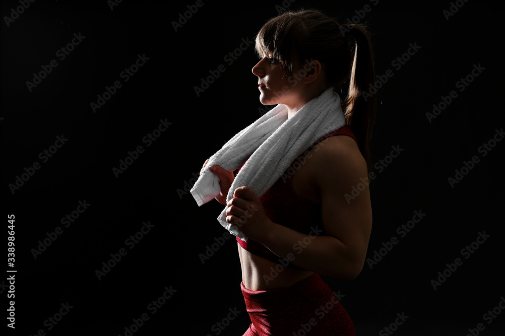 Silhouette of sporty muscular woman on dark background