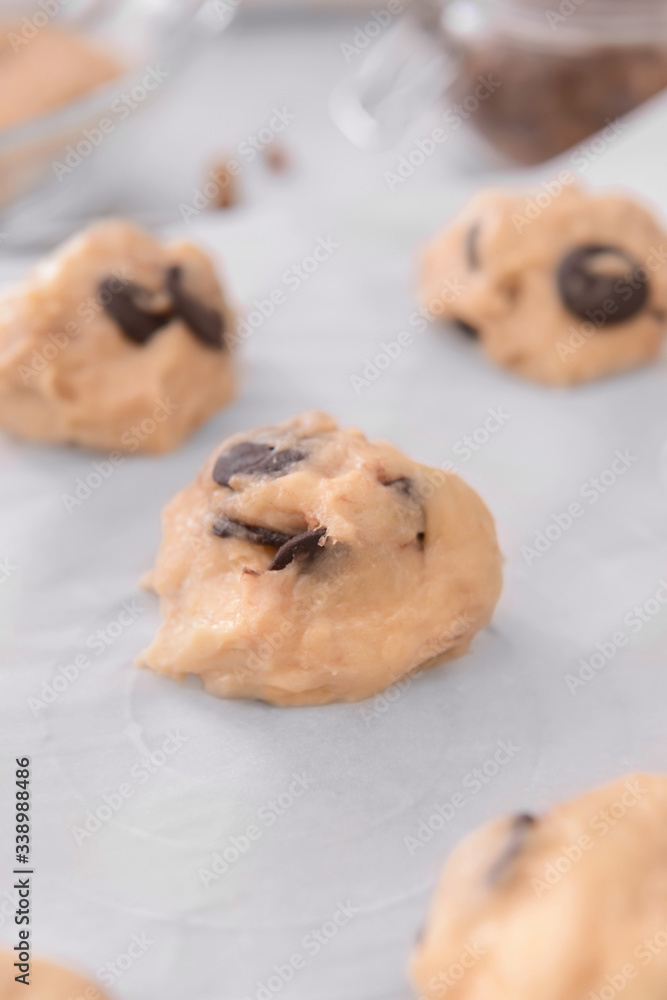 Uncooked cookies with chocolate on parchment, closeup