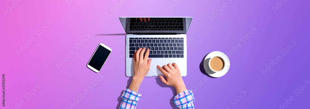 Woman using a laptop computer with a phone and a cup of coffee