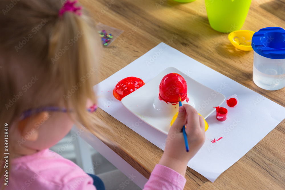 Little girl painting eggs for Easter