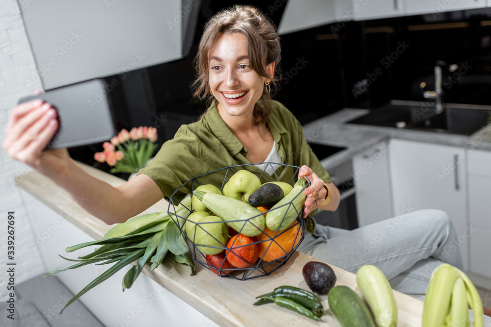 年轻女子在手机上自拍或视频记录健康饮食，与生i坐在一起