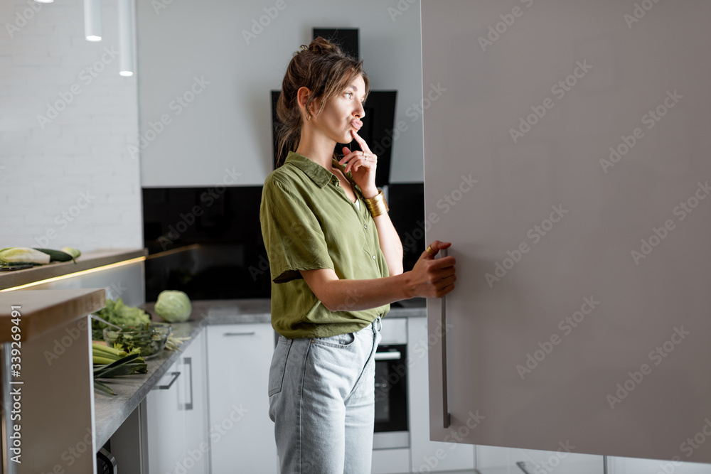 Young woman looking into the fridge, feeling hungry at night