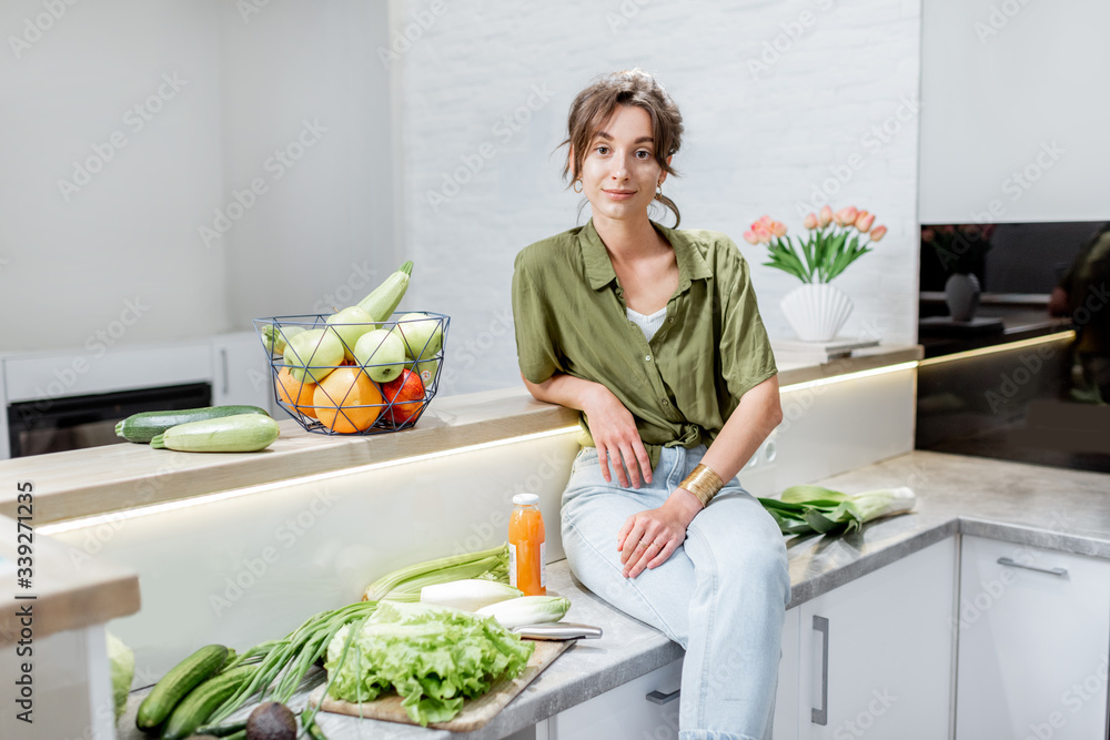 Portrait of a young and cheerful woman with healthy raw food on the kitchen at home. Vegetarianism, 