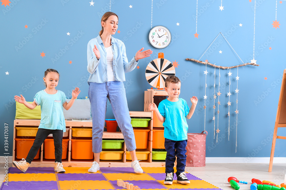 Nanny and cute little children dancing at home